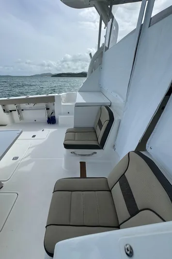 Yacht Photos Pics 2019 Pursuit OS 355 Offshore boat interior with cushioned seating, ocean view, and overcast sky.