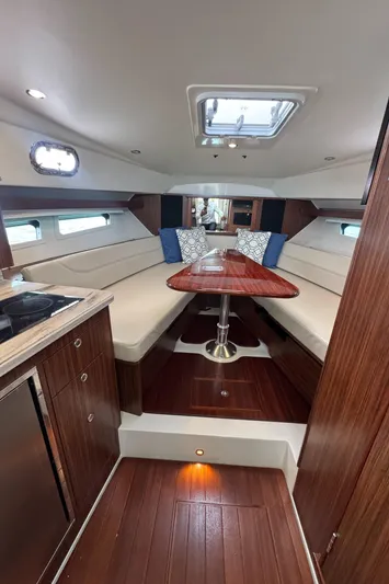  Yacht Photos Pics 2019 Pursuit OS 355 Offshore cabin interior with wood finish, seating, and table.