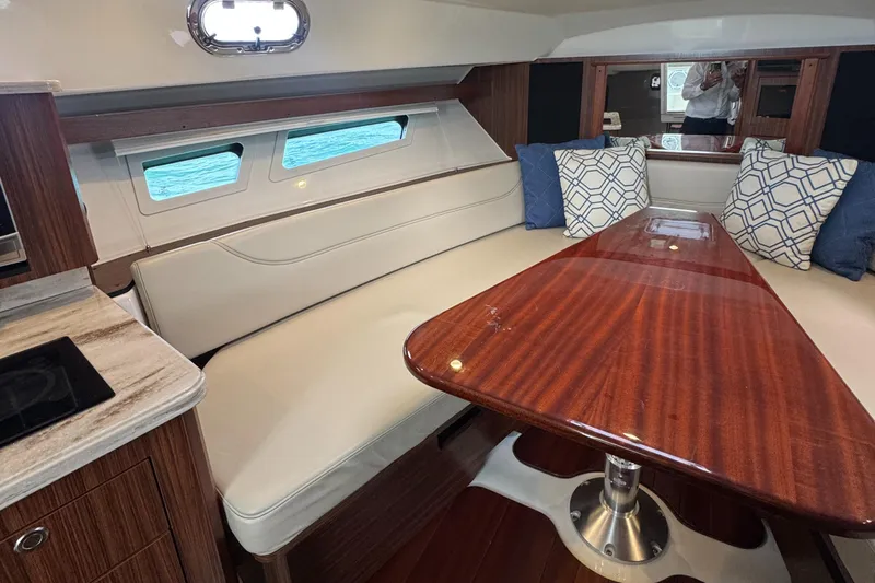  Yacht Photos Pics 2019 Pursuit OS 355 Offshore cabin with elegant wood table and cushioned seating.