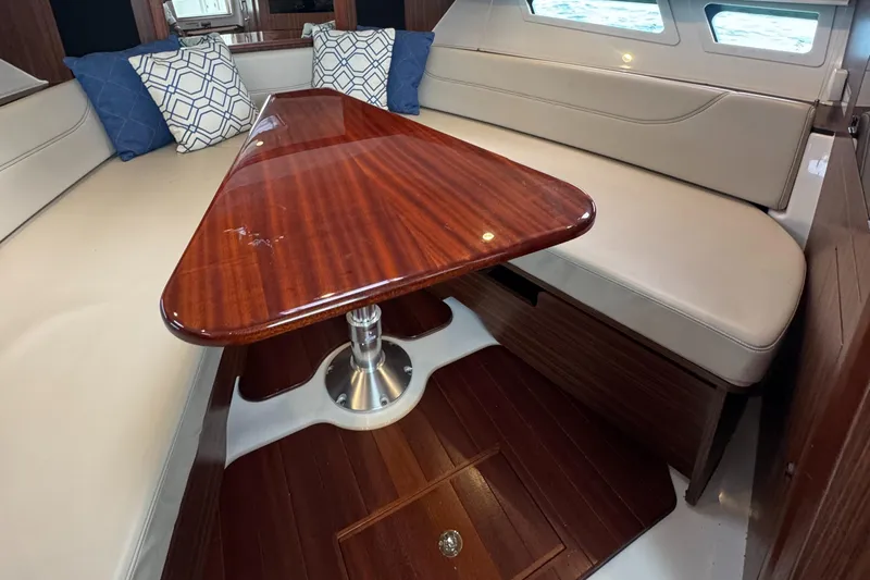  Yacht Photos Pics 2019 Pursuit OS 355 Offshore cabin with wooden table and beige seating.