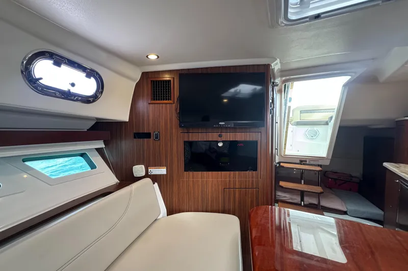  Yacht Photos Pics 2019 Pursuit OS 355 Offshore cabin interior with TV, seating, and wooden accents.