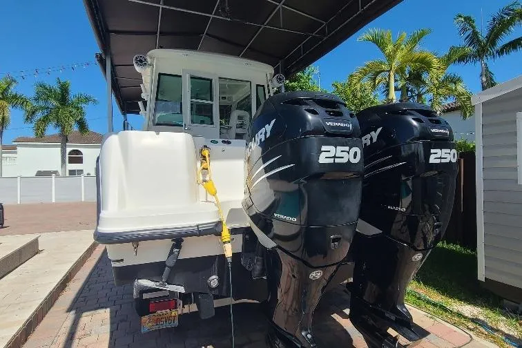 The Snapper Slapper Yacht Photos Pics 2014 Boston Whaler 315 Conquest Pilothouse with twin Mercury 250 engines, parked under a canopy.