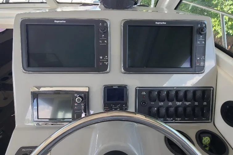 The Snapper Slapper Yacht Photos Pics Control panel of 2014 Boston Whaler 315 Conquest Pilothouse with navigation screens and switches.