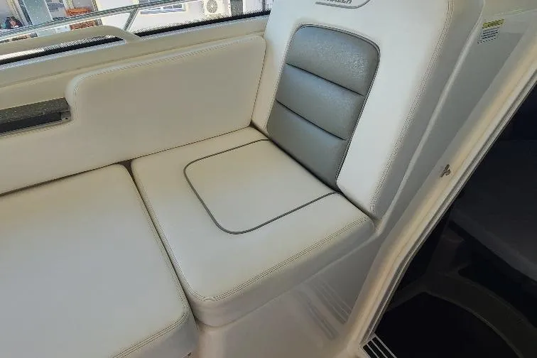 The Snapper Slapper Yacht Photos Pics 2014 Boston Whaler 315 Conquest Pilothouse interior seating, featuring white and gray cushioned seats.