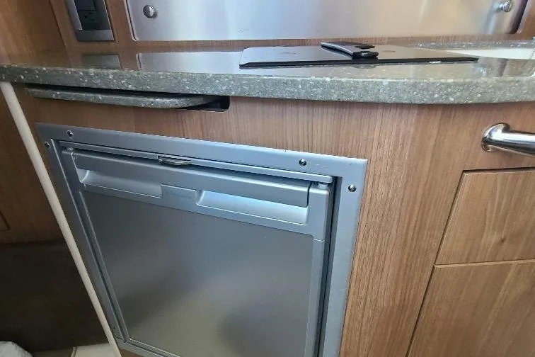 The Snapper Slapper Yacht Photos Pics 2014 Boston Whaler 315 Conquest Pilothouse interior with compact fridge and wooden cabinetry.