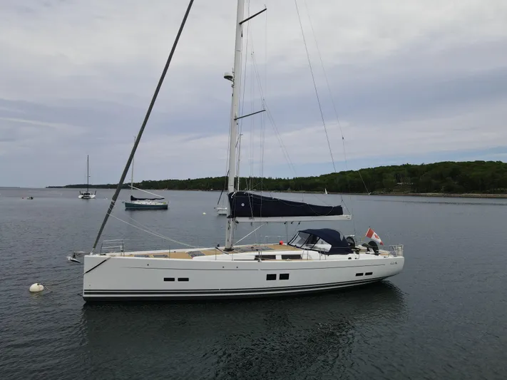 Red's Goose Yacht Photos Pics Sailing yacht Hanse 575, 2016 model, anchored in calm waters with forested shoreline.