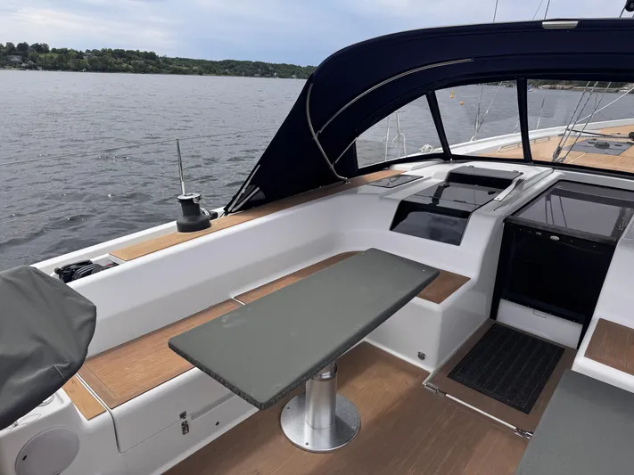 Red's Goose Yacht Photos Pics 2016 Hanse 575 yacht cockpit with table, overlooking calm waters and distant shoreline.