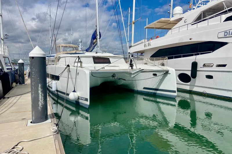  Yacht Photos Pics 2024 Fountaine Pajot Catamaran Aura 51 docked at marina, reflecting on water.