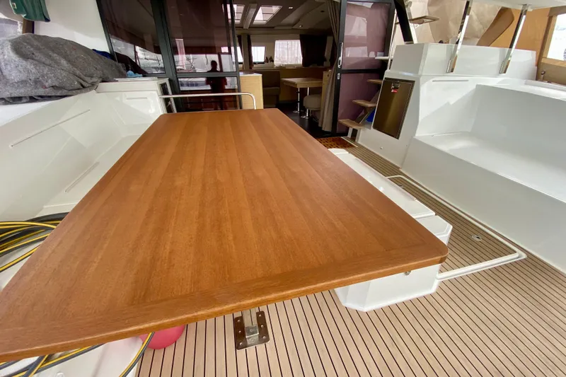  Yacht Photos Pics 2024 Fountaine Pajot Catamaran Aura 51 interior with wooden table and seating area.