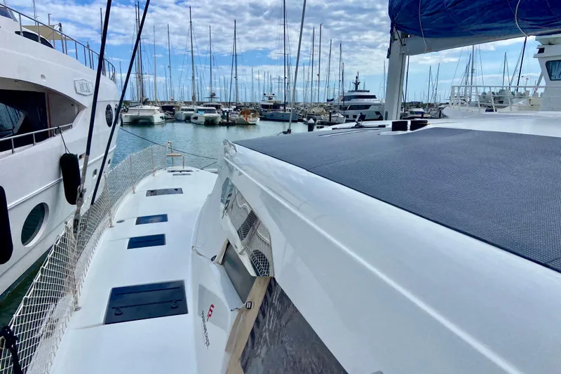  Yacht Photos Pics 2024 Fountaine Pajot Catamaran Aura 51 docked in a marina, surrounded by other boats.