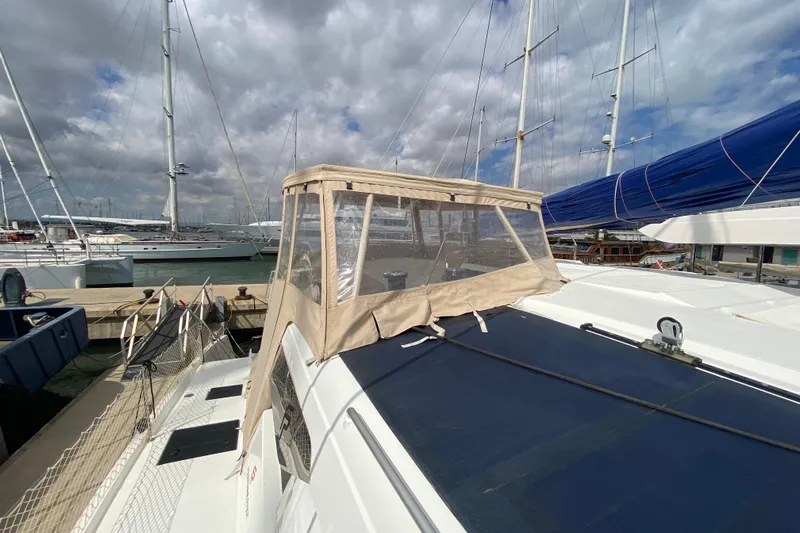  Yacht Photos Pics 2024 Fountaine Pajot Catamaran Aura 51 docked, showcasing deck and canopy under cloudy sky.