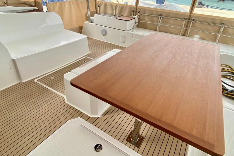  Yacht Photos Pics 2024 Fountaine Pajot Catamaran Aura 51 interior with wooden table and seating area.
