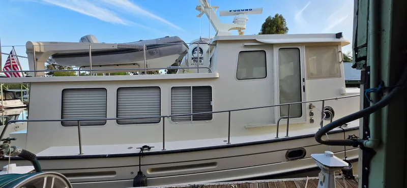 Jeanne Marie III Yacht Photos Pics 2003 Nordic Tug 42 boat docked with dinghy on top, American flag visible.