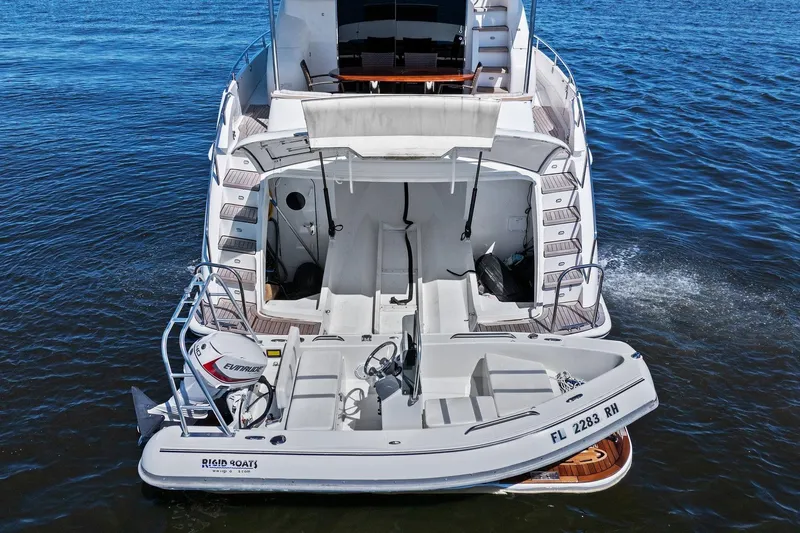  Yacht Photos Pics Lazzara yacht with tender boat on water, featuring Evinrude motor and Rigid Boats branding.