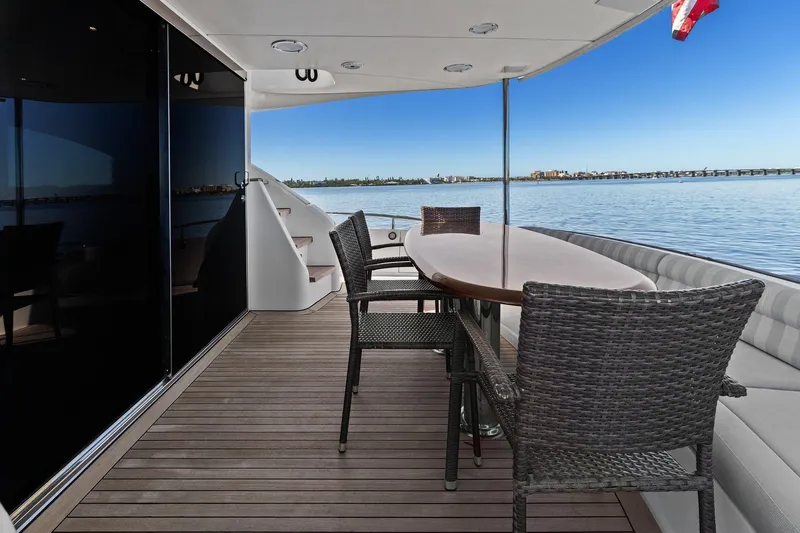  Yacht Photos Pics Luxury Lazzara yacht deck with dining area overlooking serene water and distant cityscape.
