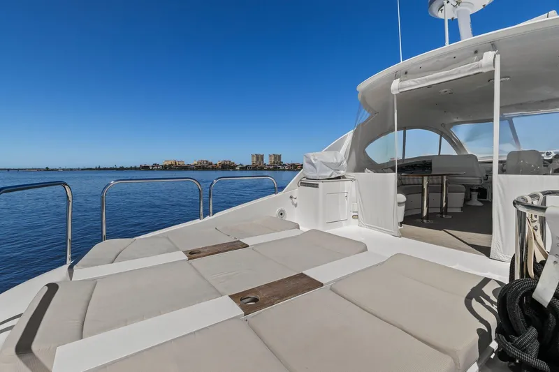  Yacht Photos Pics Luxury Lazzara yacht deck with sun loungers, overlooking calm blue waters and distant cityscape.