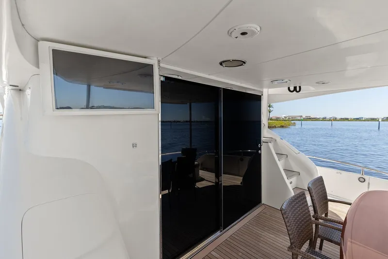  Yacht Photos Pics Luxury Lazzara yacht deck with wicker chairs, glass doors, and scenic water view.