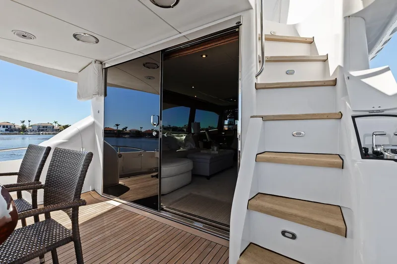  Yacht Photos Pics Luxurious Lazzara yacht deck with wicker chairs, stairs, and glass doors overlooking water.