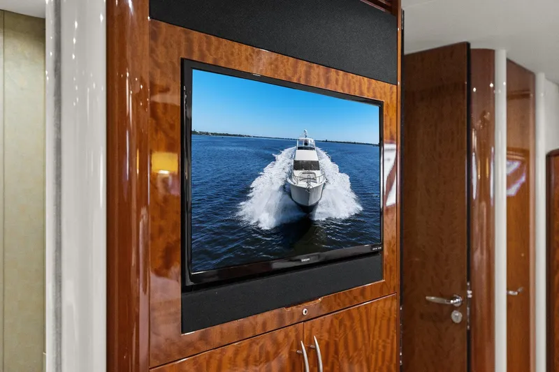  Yacht Photos Pics Flat-screen TV displaying a Lazzara yacht cruising on water, mounted on a wooden wall.