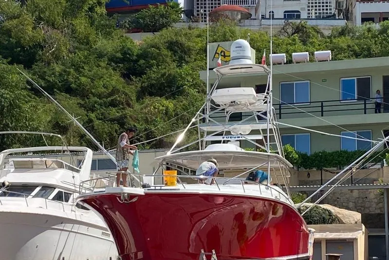  Yacht Photos Pics 2004 Cabo 45 Express Los Suenos Edition boat docked, with people on deck, surrounded by greenery.