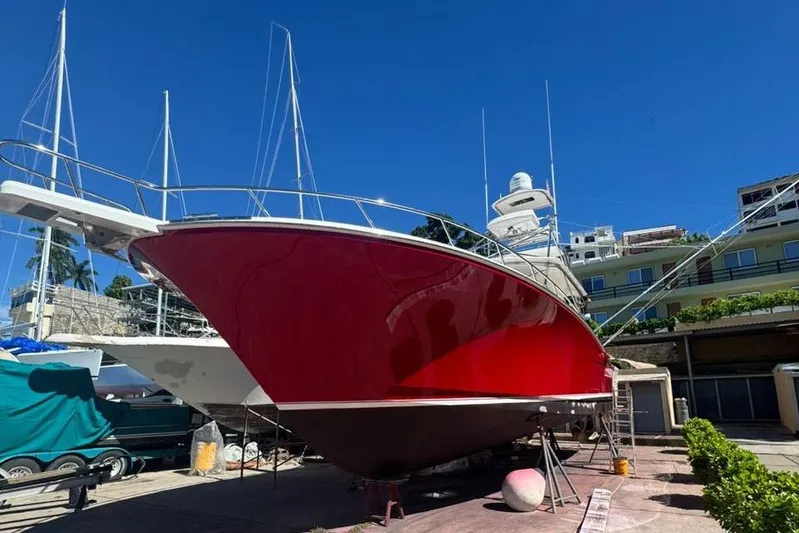  Yacht Photos Pics Red 2004 Cabo 45 Express Los Suenos Edition boat on dry dock under clear blue sky.