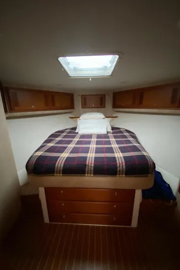  Yacht Photos Pics 2004 Cabo 45 Express Los Suenos Edition cabin with plaid bedding and wooden storage.