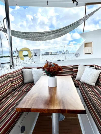  Yacht Photos Pics Luxurious Lagoon 420 yacht interior with striped seating, wooden table, and scenic ocean view.