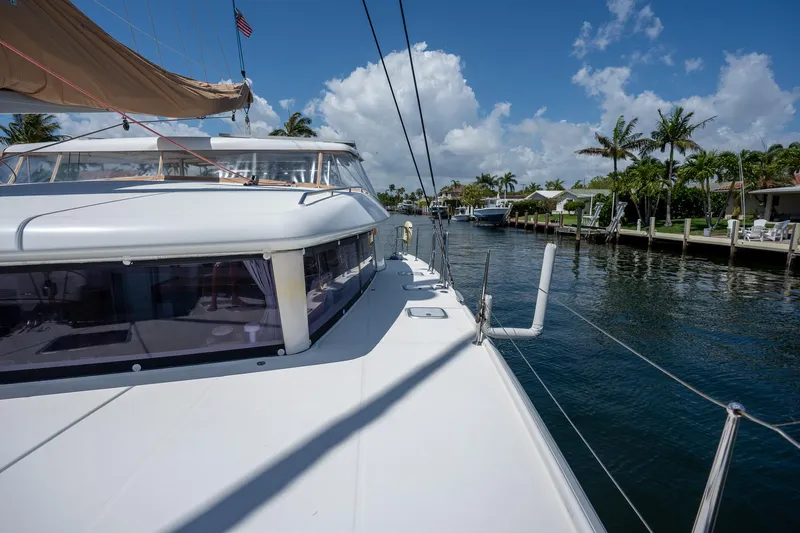  Yacht Photos Pics 2009 Lagoon 420 catamaran sailing in a sunny, tropical canal with palm trees.