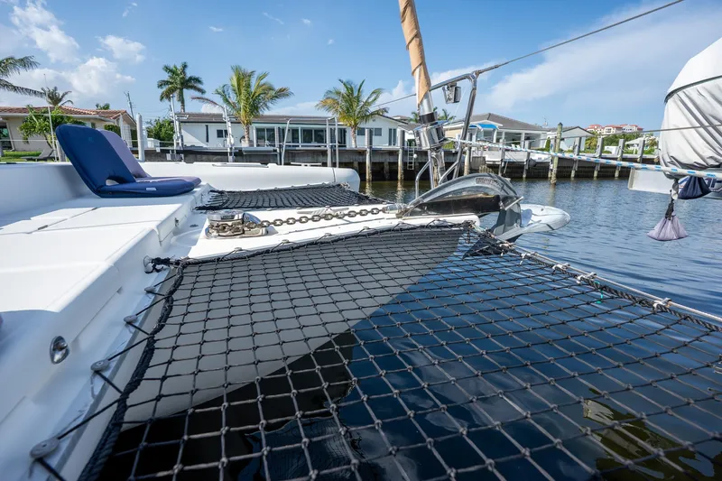  Yacht Photos Pics 2009 Lagoon 420 catamaran with netting, docked near waterfront homes and palm trees.