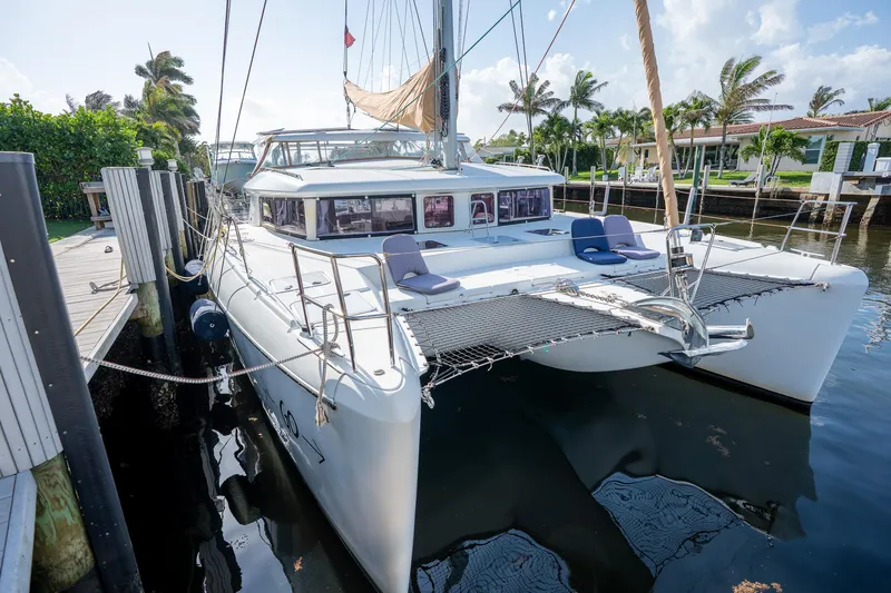  Yacht Photos Pics 2009 Lagoon 420 catamaran docked, featuring spacious deck and netting, surrounded by palm trees.