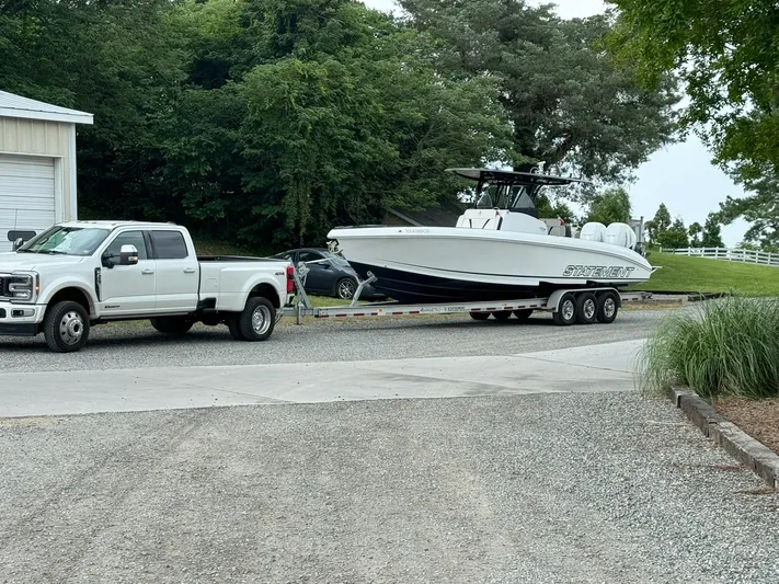  Yacht Photos Pics White truck towing 2018 Statement 35 CC boat on a trailer, parked on gravel driveway.