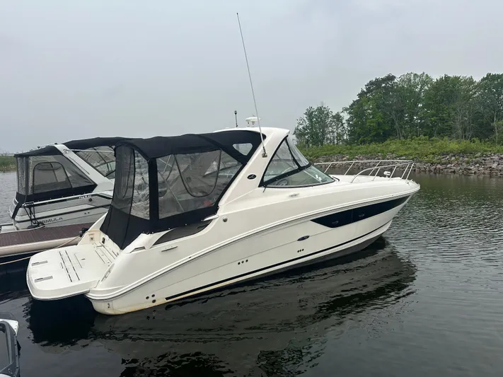  Yacht Photos Pics 2017 Sea Ray Sundancer 310 boat docked on calm water, overcast sky.