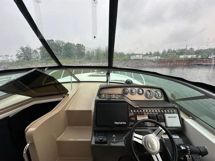  Yacht Photos Pics 2017 Sea Ray Sundancer 310 helm with navigation controls and gauges, overlooking a rainy waterfront.