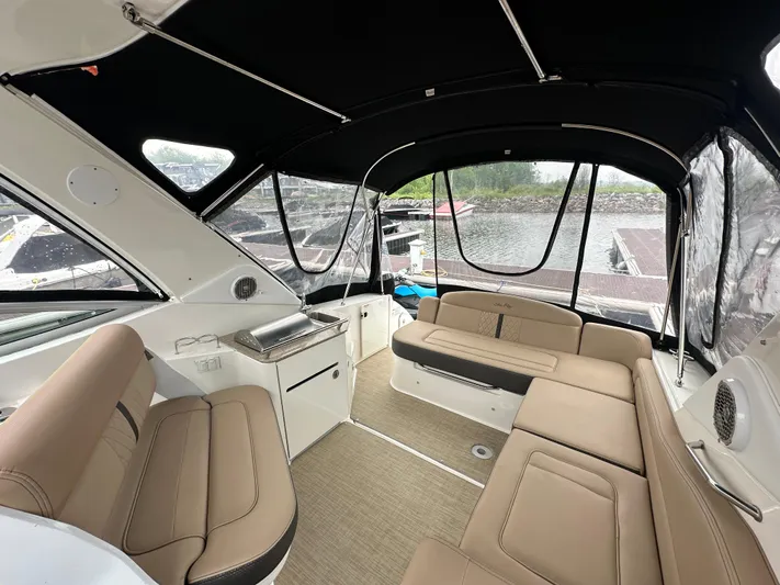  Yacht Photos Pics 2017 Sea Ray Sundancer 310 interior with beige seating and black canopy, docked by the water.