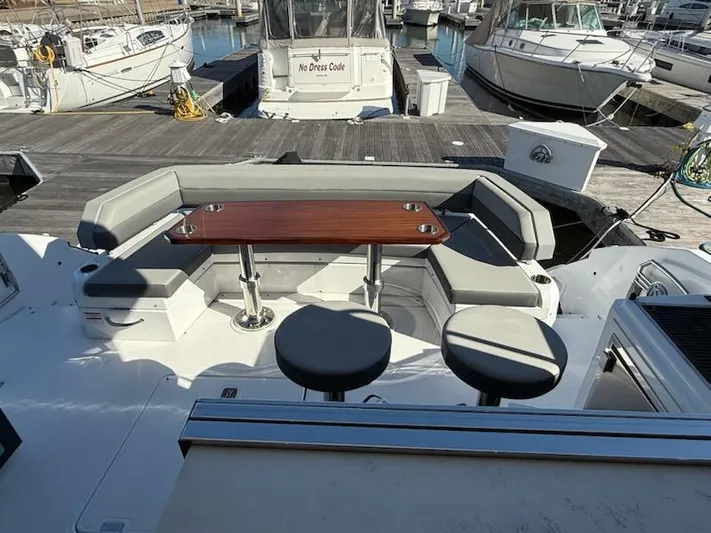 Emilia Yacht Photos Pics Outdoor seating area on 2022 Cruisers Yachts 54 Cantius, featuring a wooden table and cushioned seats.