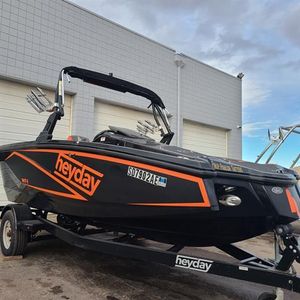 2018 Heyday WT-1 SC boat on trailer, black with orange accents, parked outside.