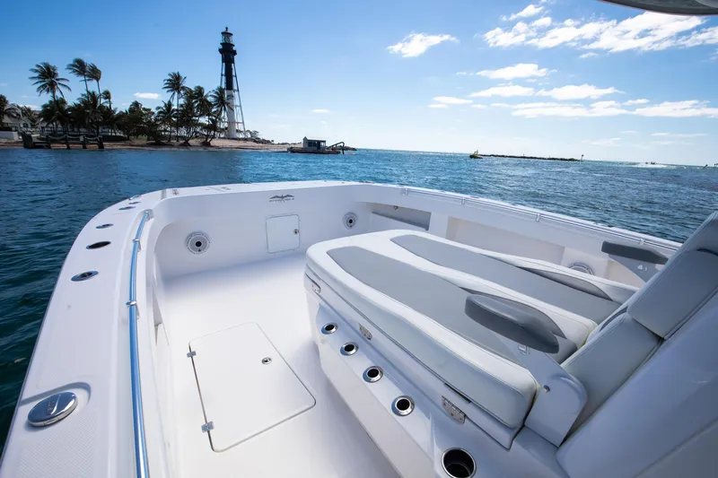 Emanon Yacht Photos Pics 2021 Invincible 35 Center Console boat with spacious deck, near a lighthouse and palm trees.