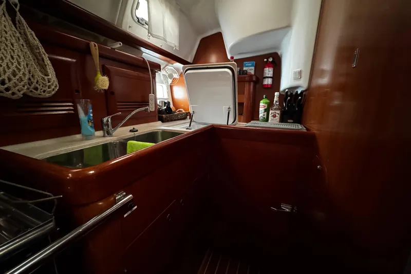 Still In The Moment Yacht Photos Pics Galley kitchen in 2007 Beneteau 423 sailboat with wooden cabinetry and stainless steel sink.