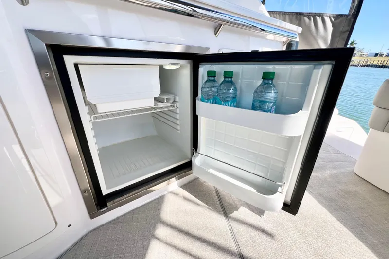 Aventuras Yacht Photos Pics Open mini fridge on 2021 Regal 33 XO boat with water bottles inside.