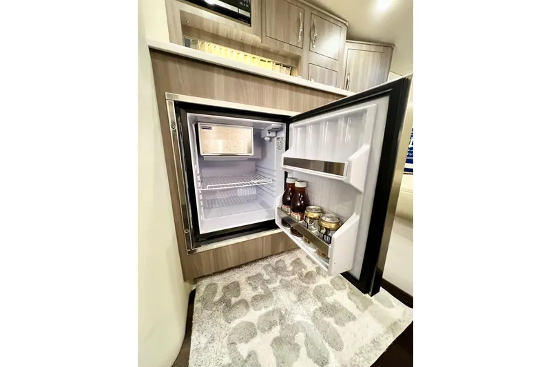 Aventuras Yacht Photos Pics 2021 Regal 33 XO boat interior with open mini fridge, stocked with beverages.