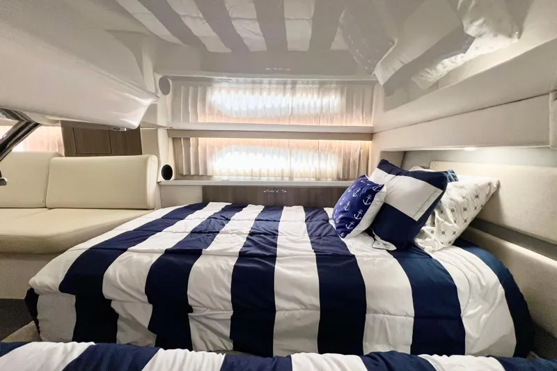 Aventuras Yacht Photos Pics Luxurious interior of 2021 Regal 33 XO yacht with striped bedding and nautical-themed pillows.