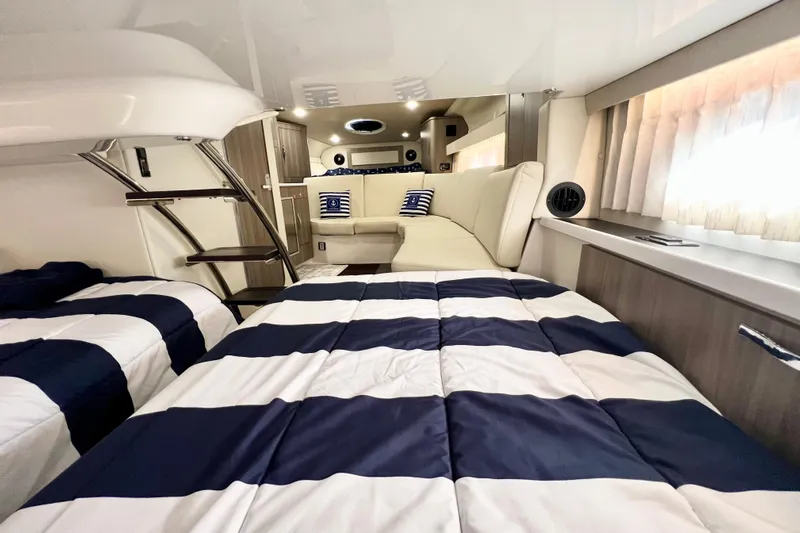 Aventuras Yacht Photos Pics Luxurious interior of 2021 Regal 33 XO yacht with striped bedding and cozy seating area.