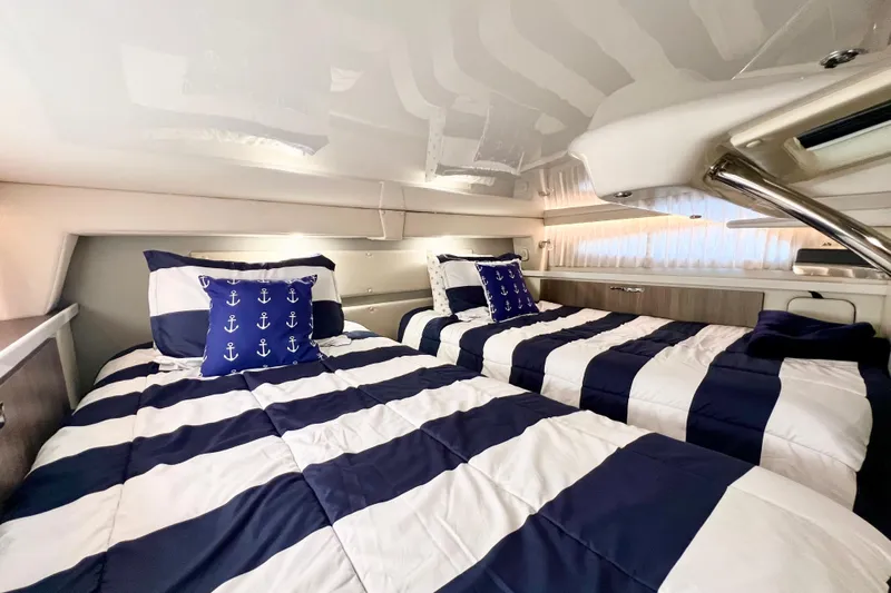 Aventuras Yacht Photos Pics 2021 Regal 33 XO cabin with striped bedding and nautical-themed pillows.
