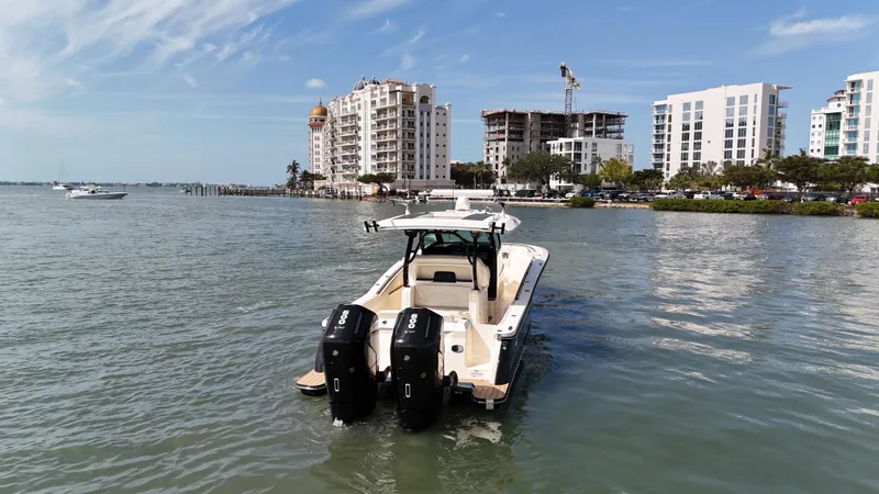 Yacht Photos Pics 2024 Scout 377 LXF boat cruising near modern waterfront buildings.