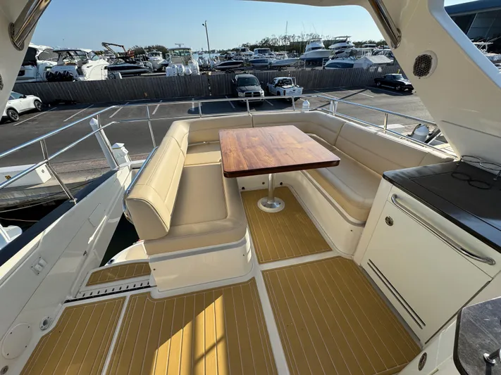 Bateau D’amis Yacht Photos Pics 2016 Sea Ray 510 Fly yacht with spacious outdoor seating and wooden table on deck.