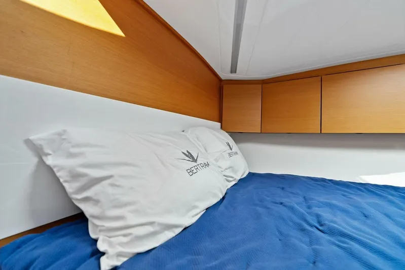 Still Dancing Yacht Photos Pics Cozy cabin interior of 2017 Bertram 35 Flybridge with blue bedding and wooden cabinets.