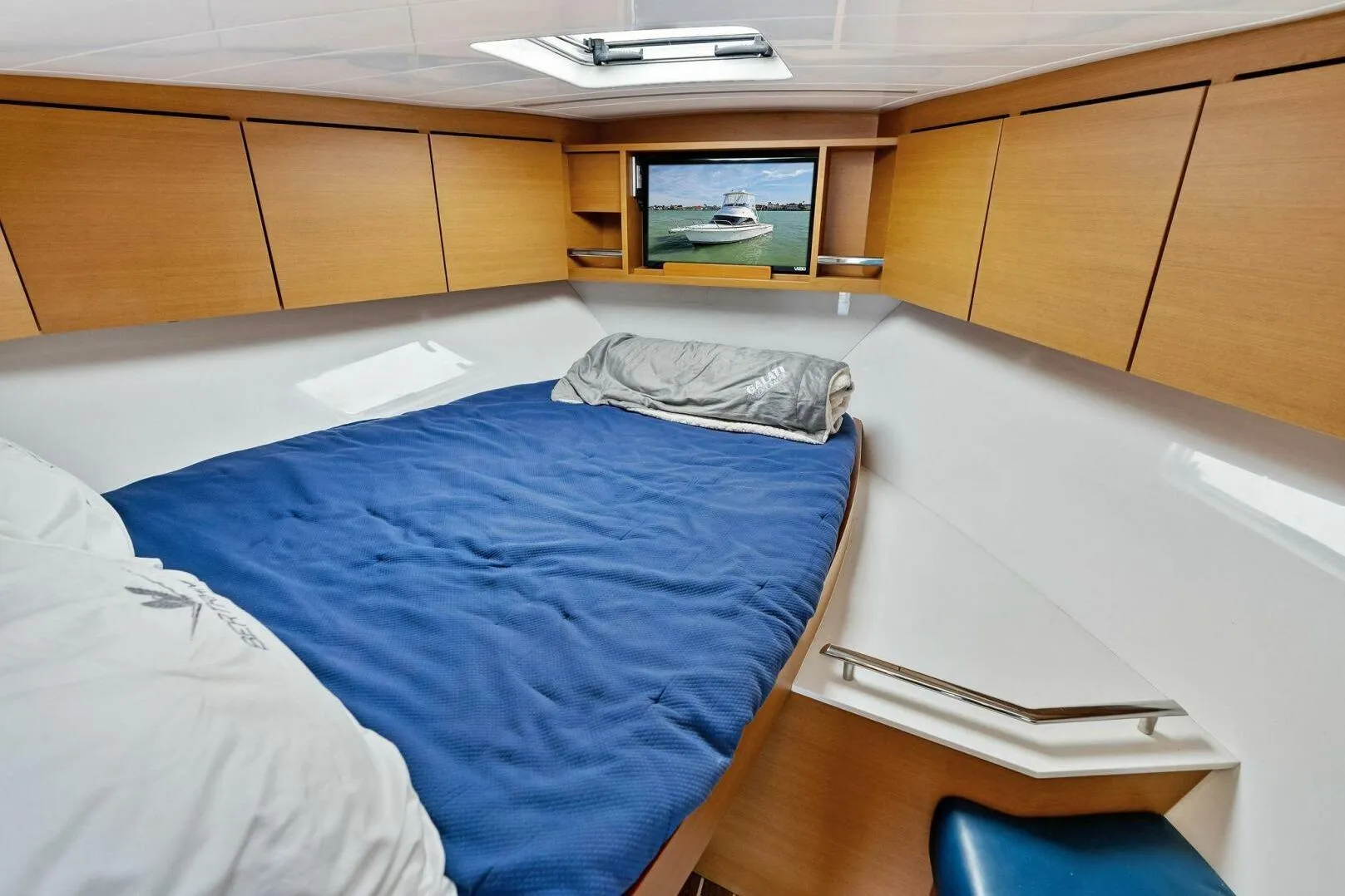 2017 Bertram 35 Flybridge cabin with blue bedding and wooden storage cabinets.