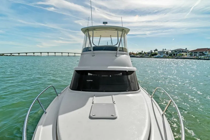 Still Dancing Yacht Photos Pics 2017 Bertram 35 Flybridge yacht on serene water with bridge and houses in background.