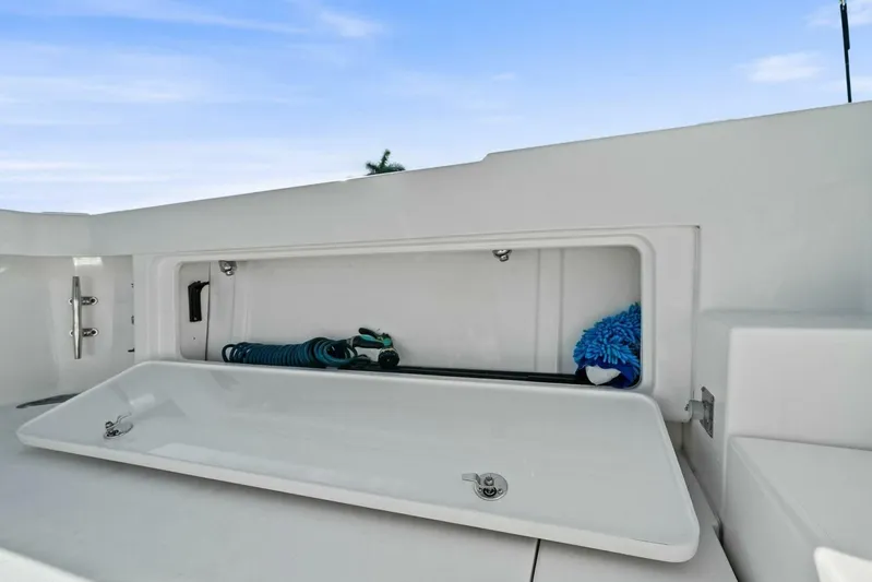 Still Dancing Yacht Photos Pics Storage compartment on 2017 Bertram 35 Flybridge boat, featuring cleaning supplies and hose.