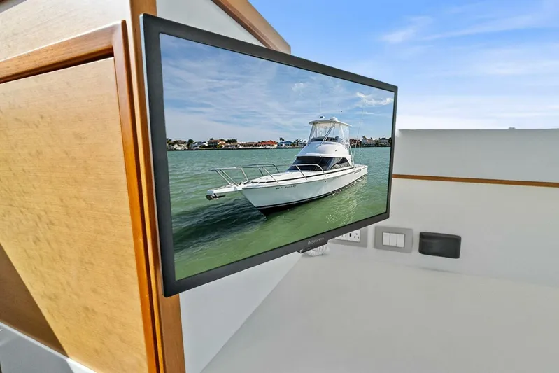 Still Dancing Yacht Photos Pics Flat-screen TV displaying a 2017 Bertram 35 Flybridge yacht on calm water.